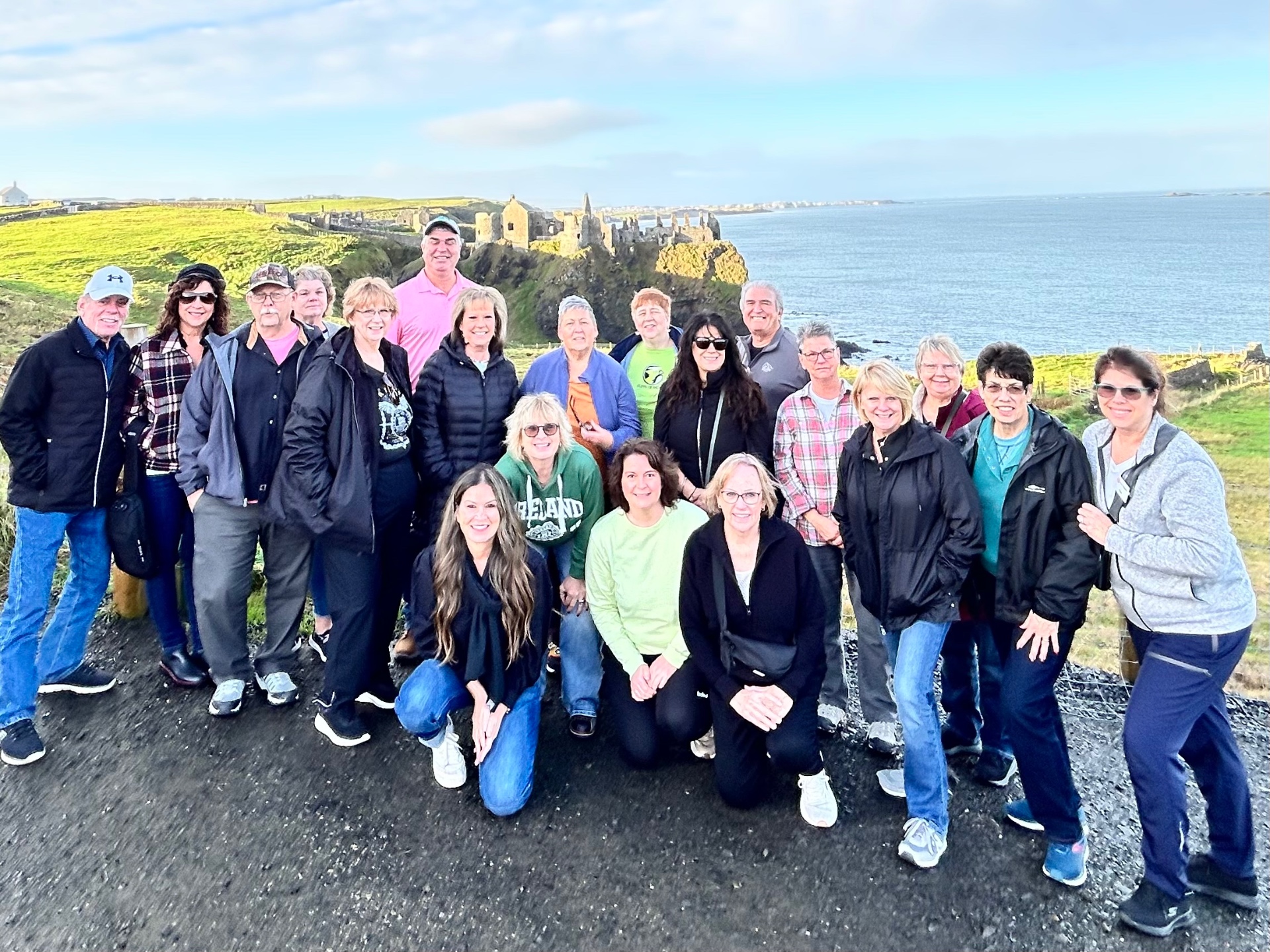 Group of travelers with Judy Adams in Ireland overlooking a coastal castle ruin